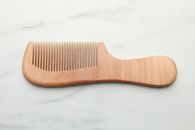 Photo of One wooden hair comb on white marble table, top view