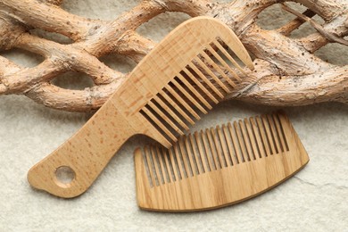 Photo of Wooden hair combs and tree branch on beige background, closeup