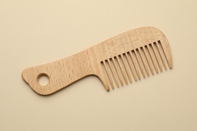 Photo of One wooden hair comb on beige background, top view