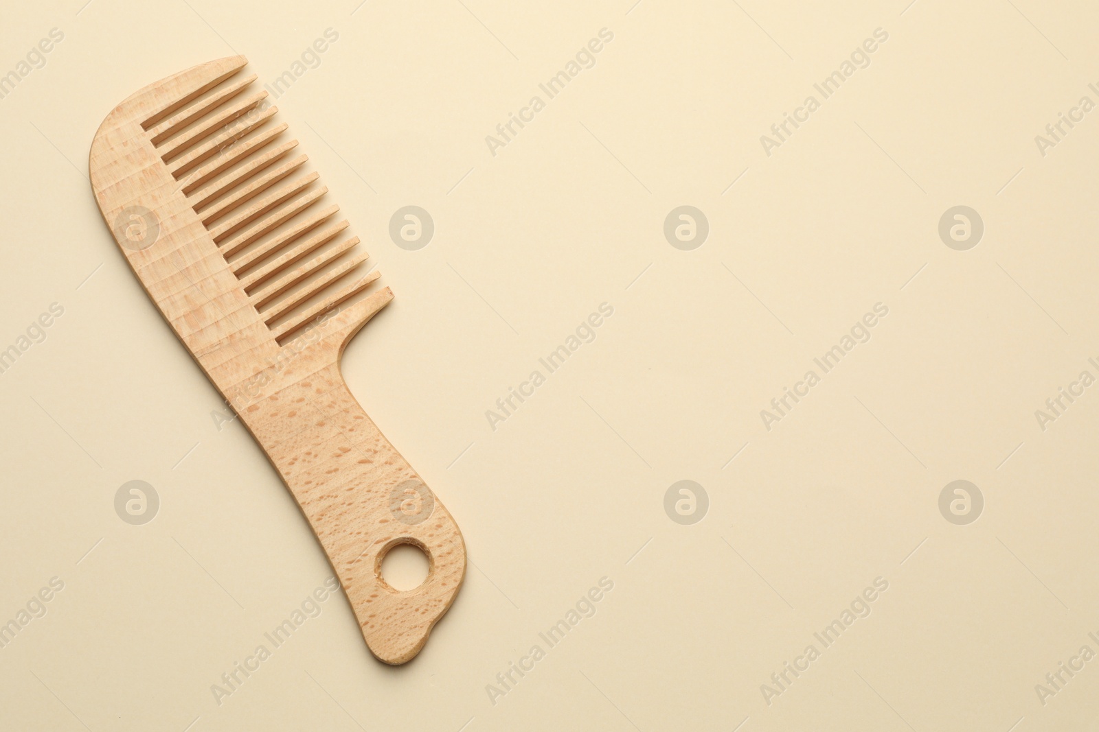 Photo of One wooden hair comb on beige background, top view. Space for text