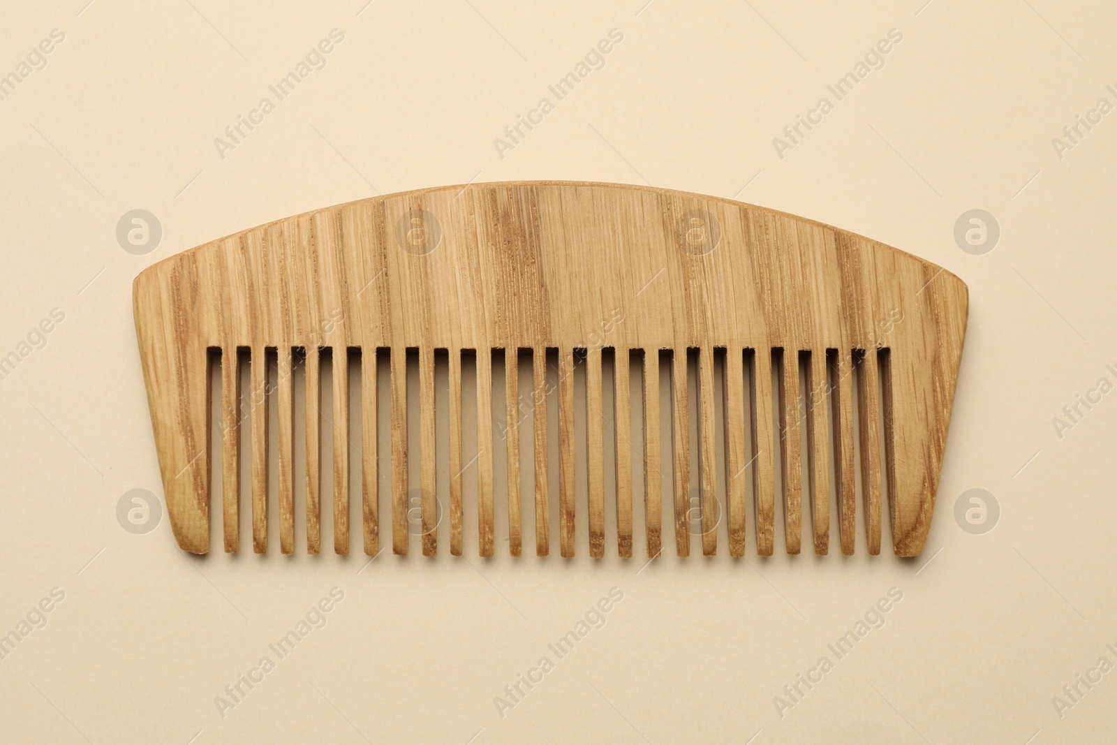 Photo of One wooden hair comb on beige background, top view