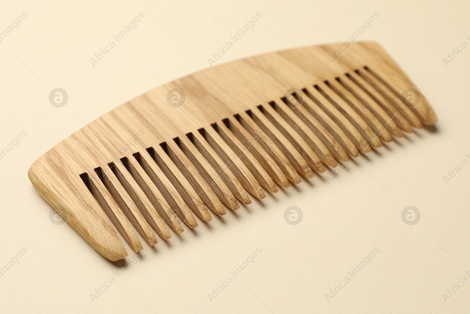 Photo of One wooden hair comb on beige background, closeup