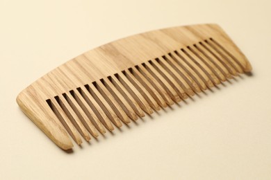 Photo of One wooden hair comb on beige background, closeup