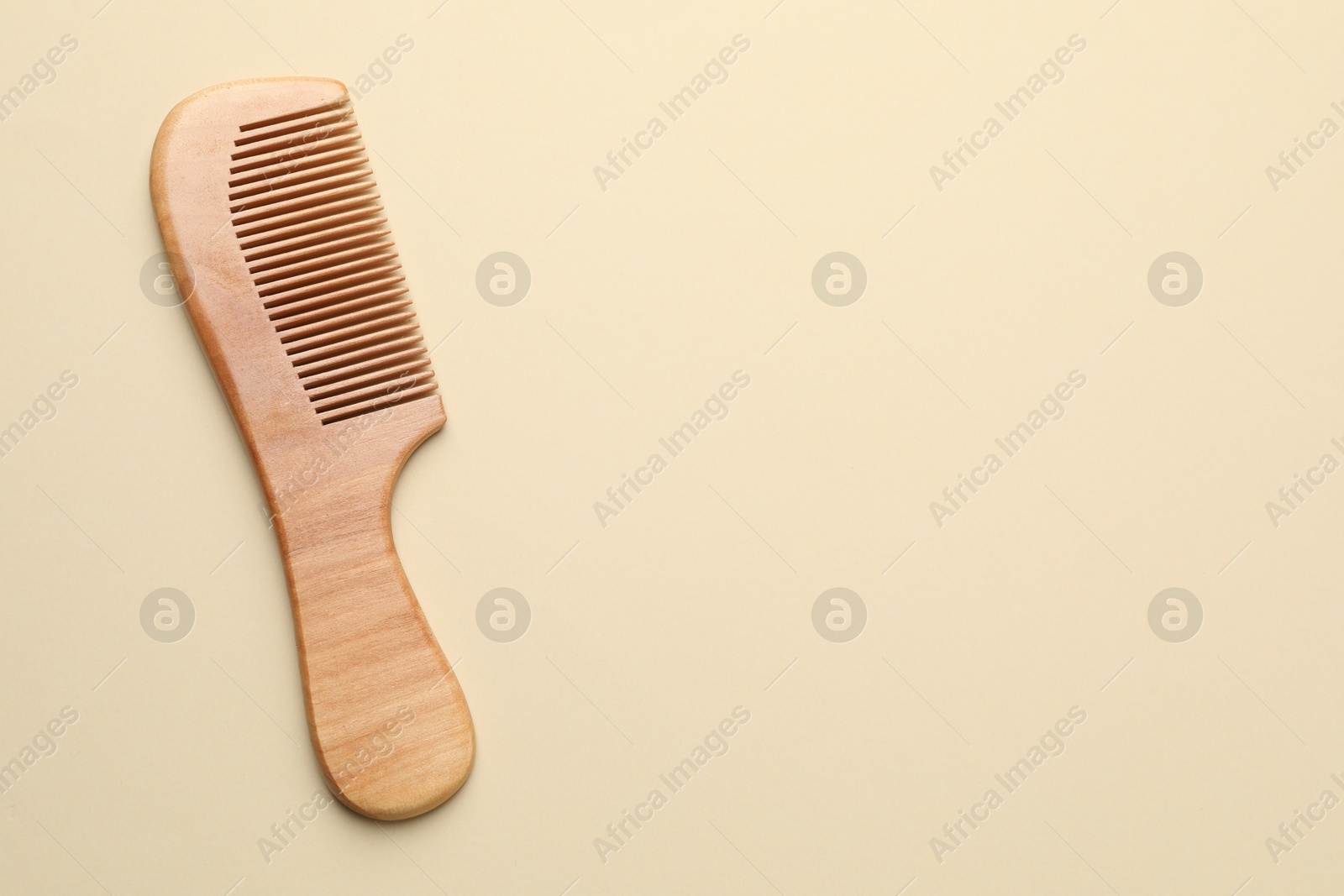 Photo of One wooden hair comb on beige background, top view. Space for text