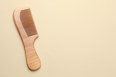 Photo of One wooden hair comb on beige background, top view. Space for text