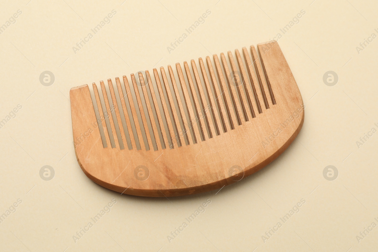 Photo of One wooden hair comb on beige background, top view