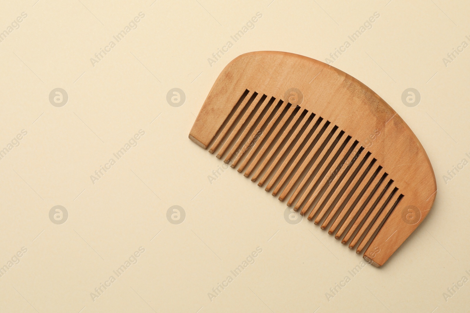 Photo of One wooden hair comb on beige background, top view. Space for text