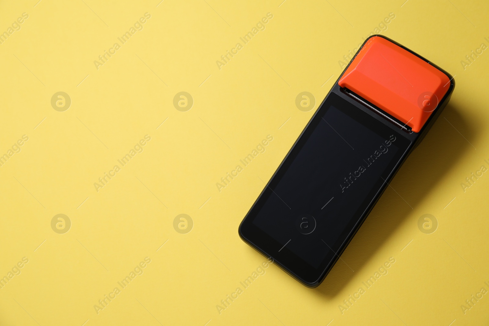 Photo of One payment terminal on yellow background, top view. Space for text