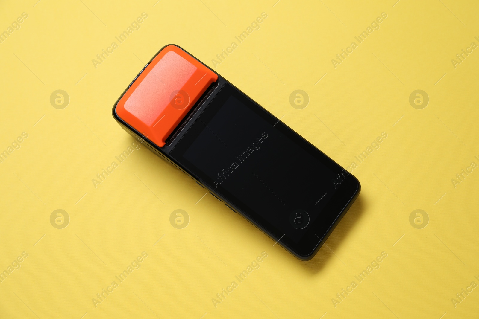 Photo of One payment terminal on yellow background, top view