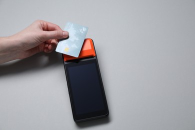 Photo of Woman with credit card using payment terminal on grey background, top view. Space for text