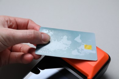 Photo of Woman with credit card using payment terminal on grey background, closeup