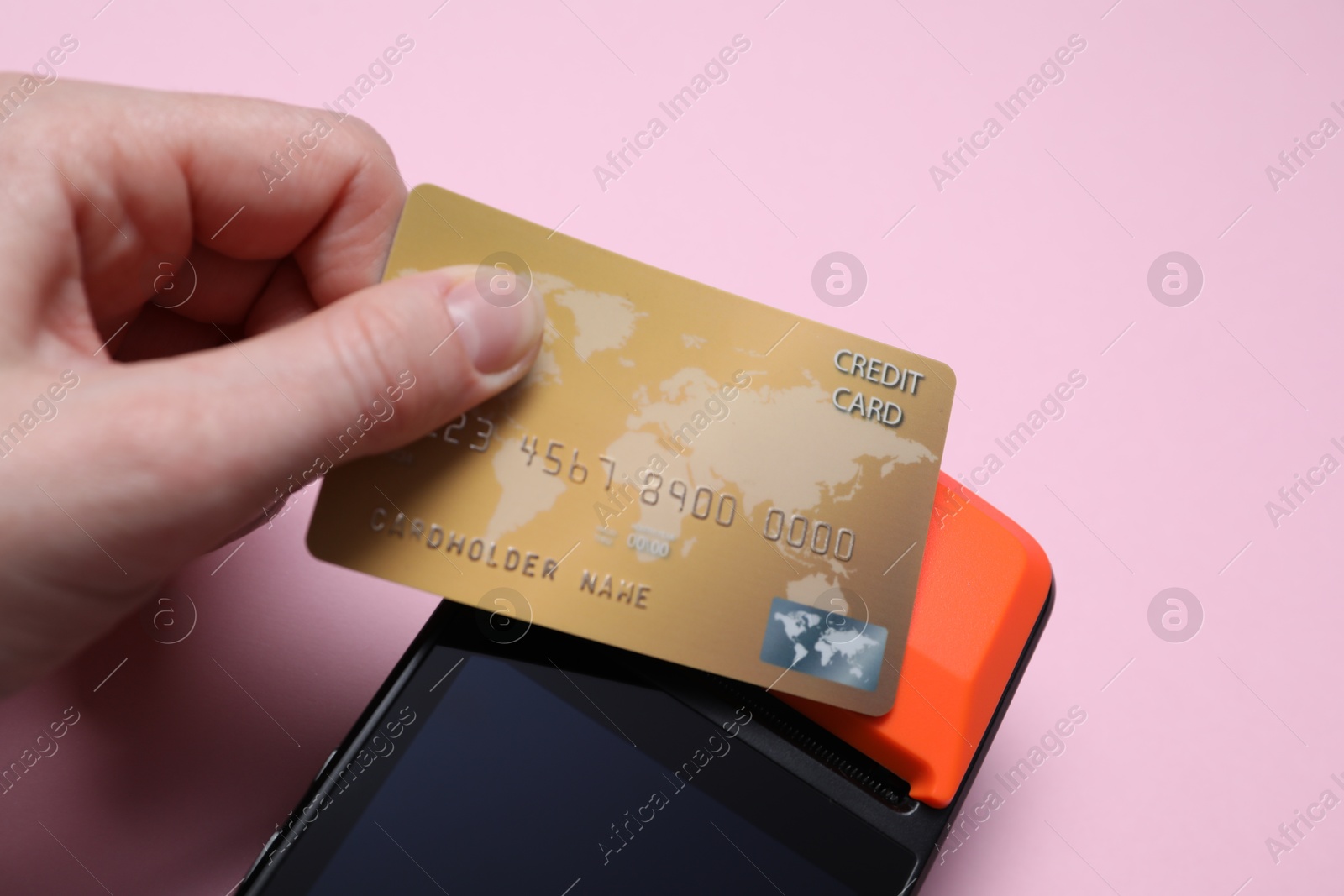 Photo of Woman with credit card using payment terminal on pink background, closeup