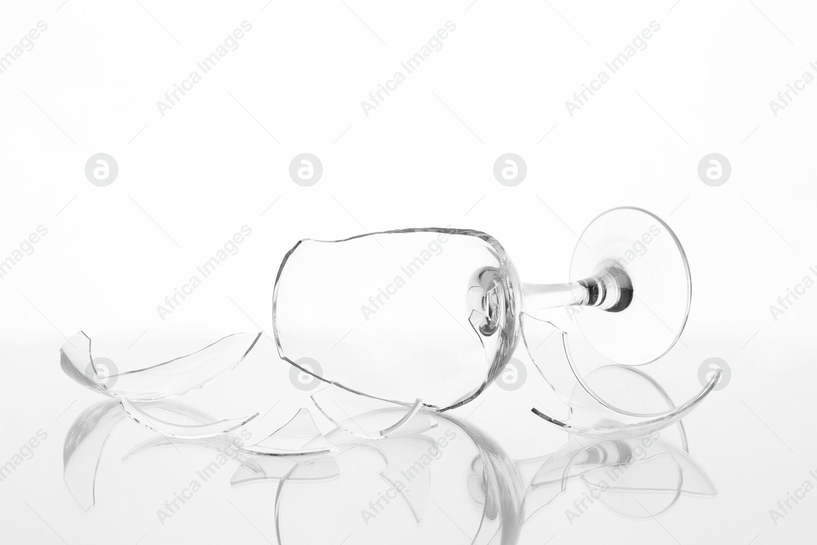 Photo of Pieces of broken wine glass on table against white background