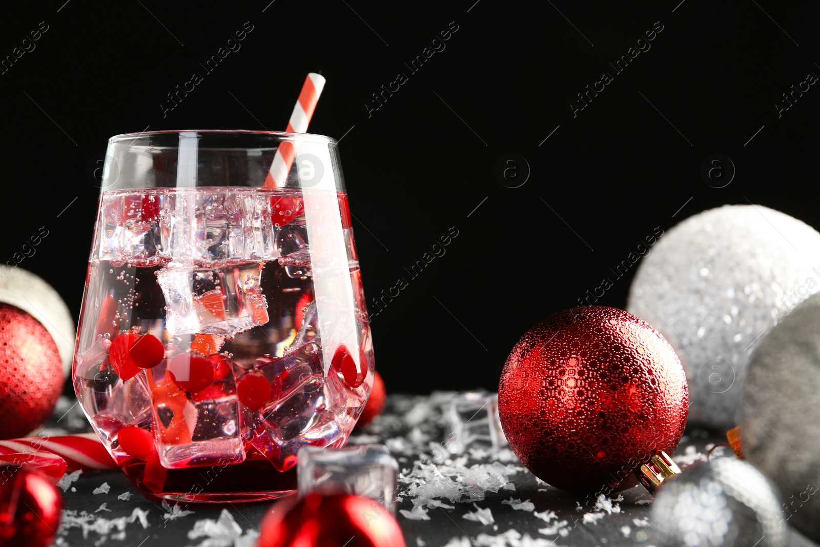 Photo of Tasty Christmas cocktail in glass, ice and decor on black table, closeup