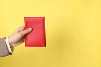 Photo of Woman holding passport in bright cover on yellow background, closeup. Space for text