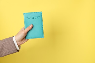 Photo of Woman holding passport in bright cover on yellow background, closeup. Space for text