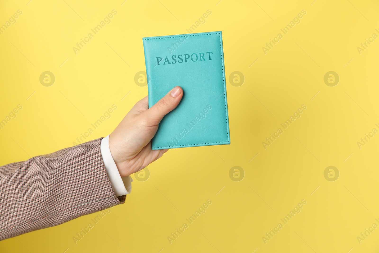 Photo of Woman holding passport in bright cover on yellow background, closeup. Space for text