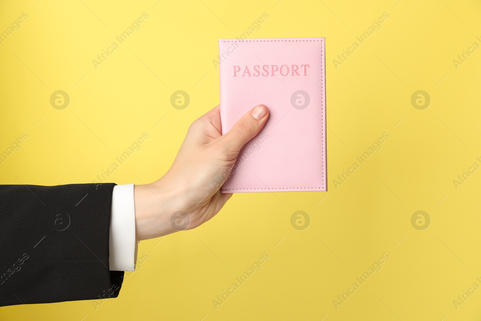 Photo of Woman holding passport in bright cover on yellow background, closeup. Space for text