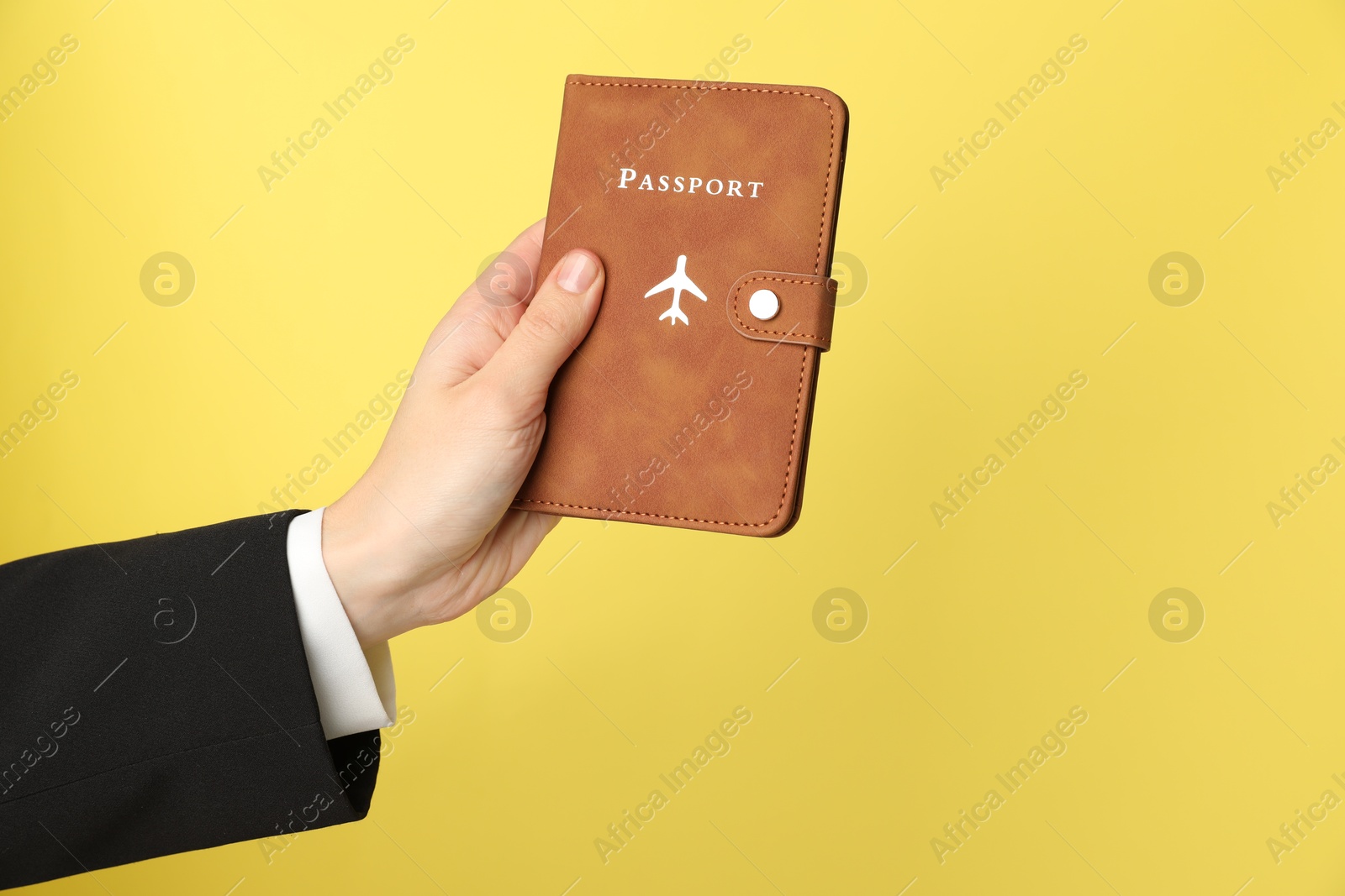 Photo of Woman holding passport in bright cover on yellow background, closeup. Space for text