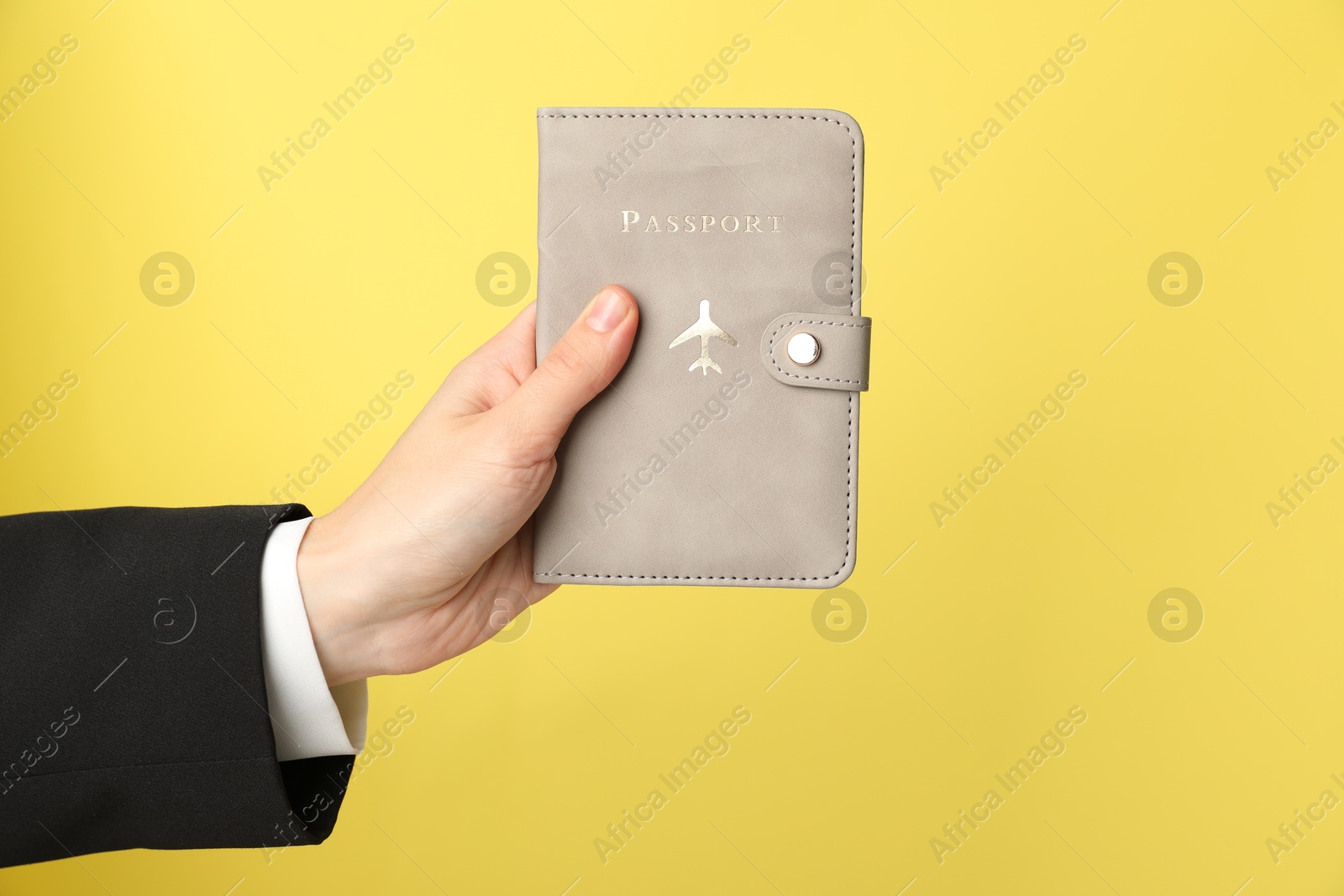 Photo of Woman holding passport in bright cover on yellow background, closeup. Space for text