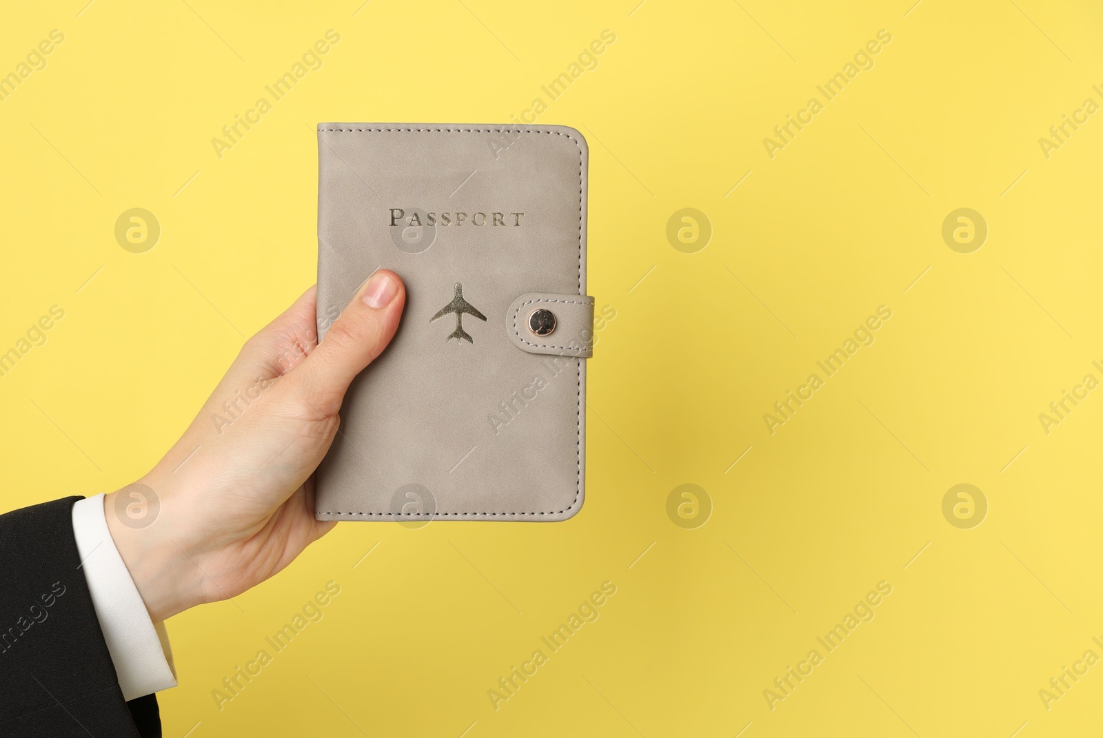 Photo of Woman holding passport in bright cover on yellow background, closeup. Space for text