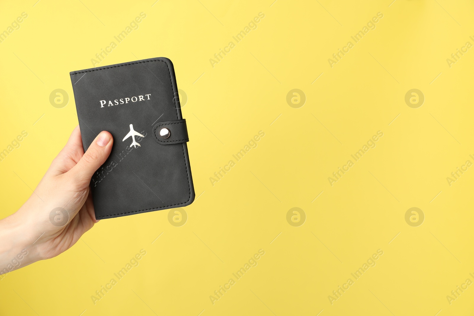 Photo of Woman holding passport in bright cover on yellow background, closeup. Space for text