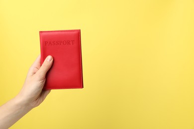 Photo of Woman holding passport in bright cover on yellow background, closeup. Space for text