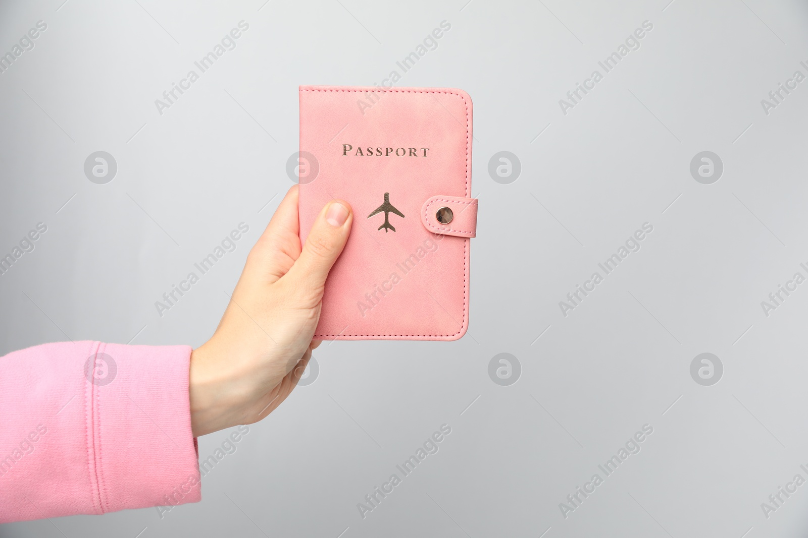 Photo of Woman holding passport in bright cover on grey background, closeup. Space for text