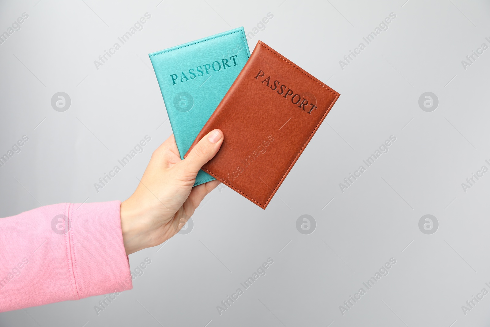 Photo of Woman holding passports in bright covers on grey background, closeup. Space for text