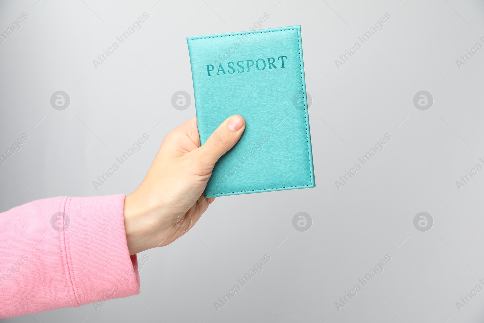 Photo of Woman holding passport in bright cover on grey background, closeup