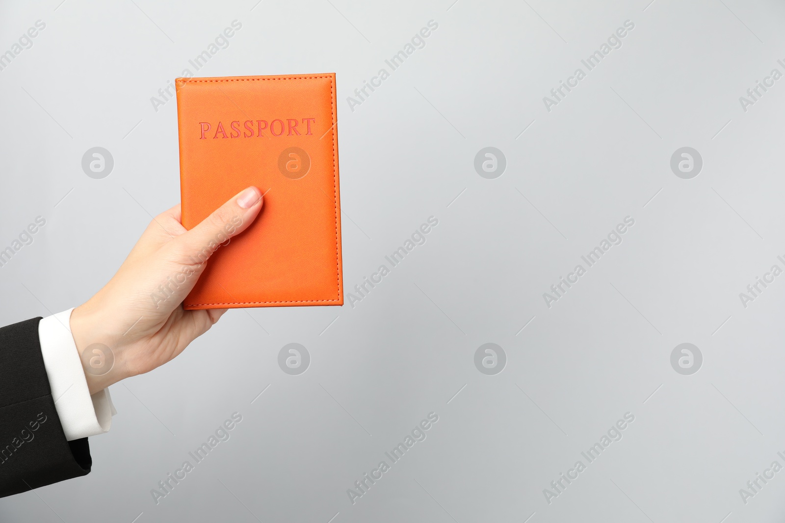 Photo of Woman holding passport in bright cover on grey background, closeup. Space for text