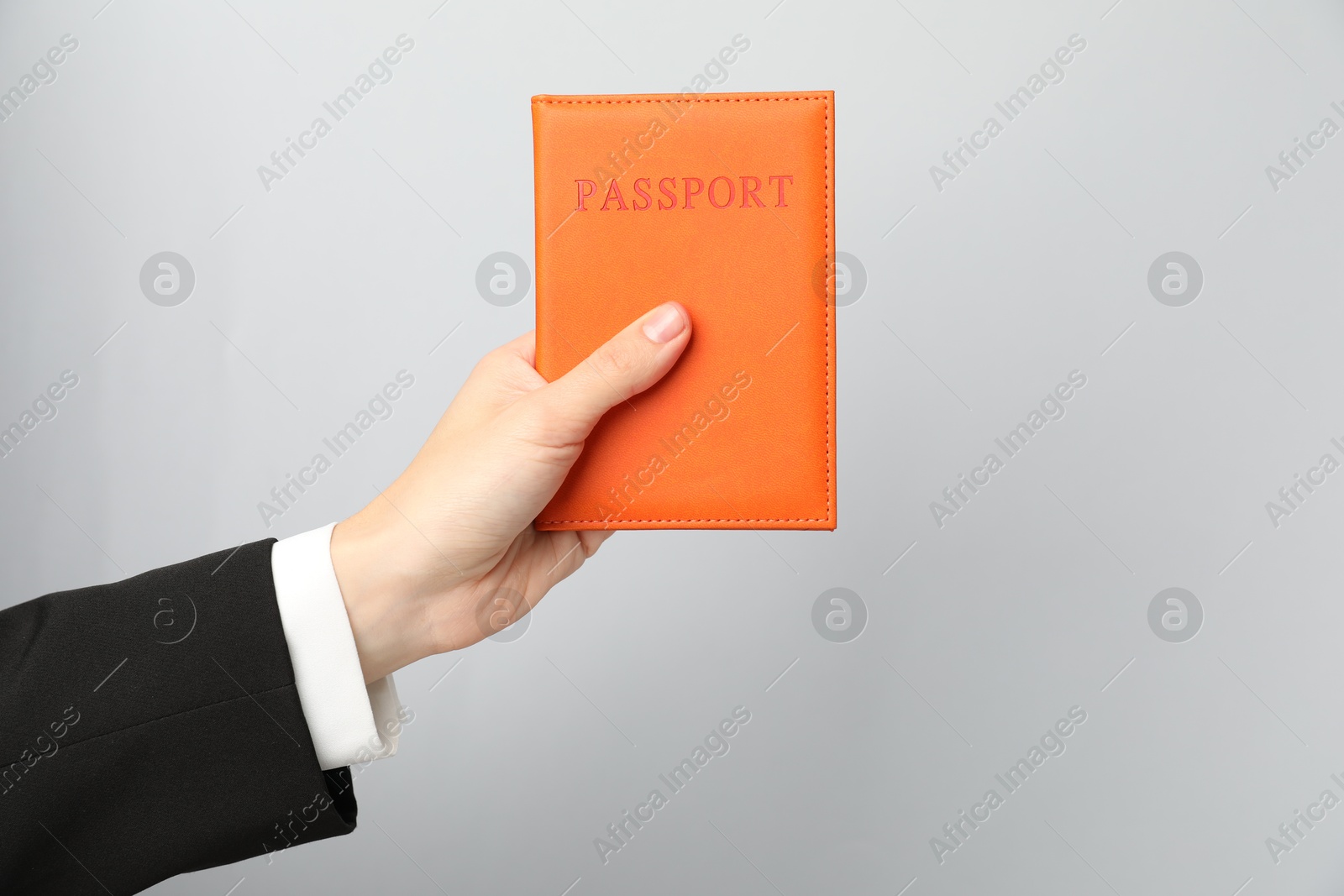 Photo of Woman holding passport in bright cover on grey background, closeup. Space for text