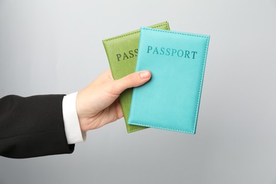 Photo of Woman holding passports in bright covers on grey background, closeup