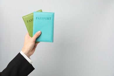 Photo of Woman holding passports in bright covers on grey background, closeup. Space for text