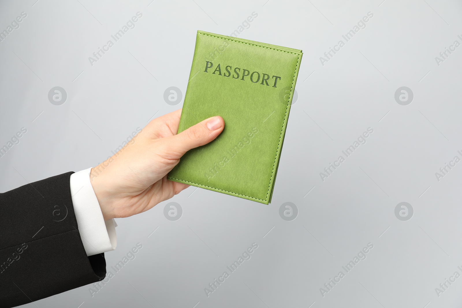 Photo of Woman holding passport in bright cover on grey background, closeup. Space for text