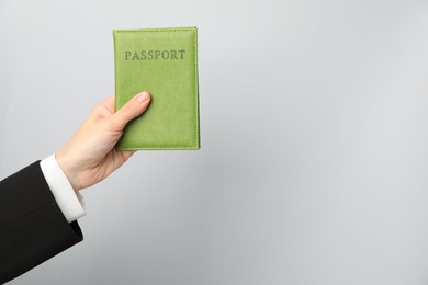 Photo of Woman holding passport in bright cover on grey background, closeup. Space for text