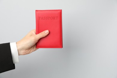 Photo of Woman holding passport in bright cover on grey background, closeup. Space for text