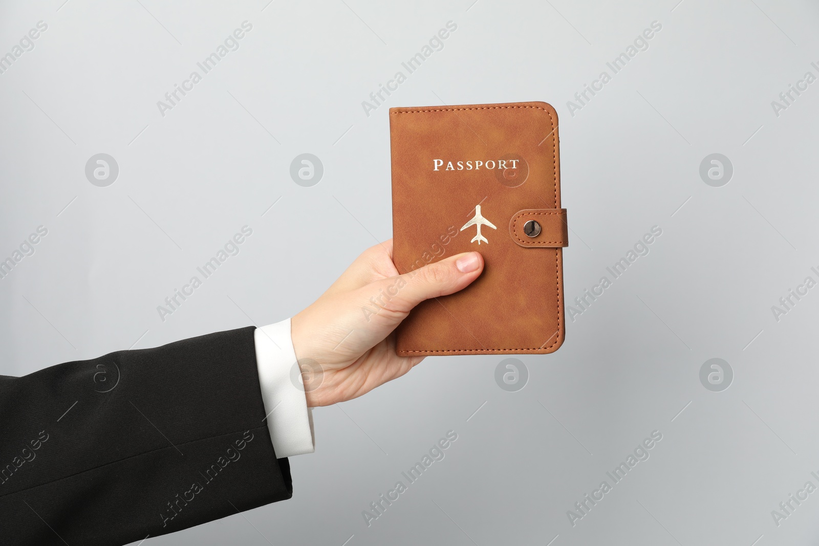 Photo of Woman holding passport in bright cover on grey background, closeup