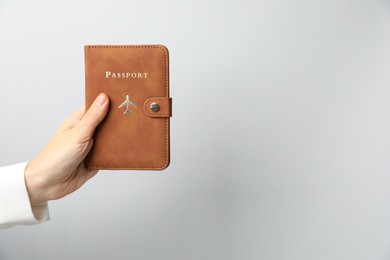 Photo of Woman holding passport in bright cover on grey background, closeup. Space for text