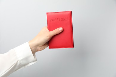 Photo of Woman holding passport in bright cover on grey background, closeup