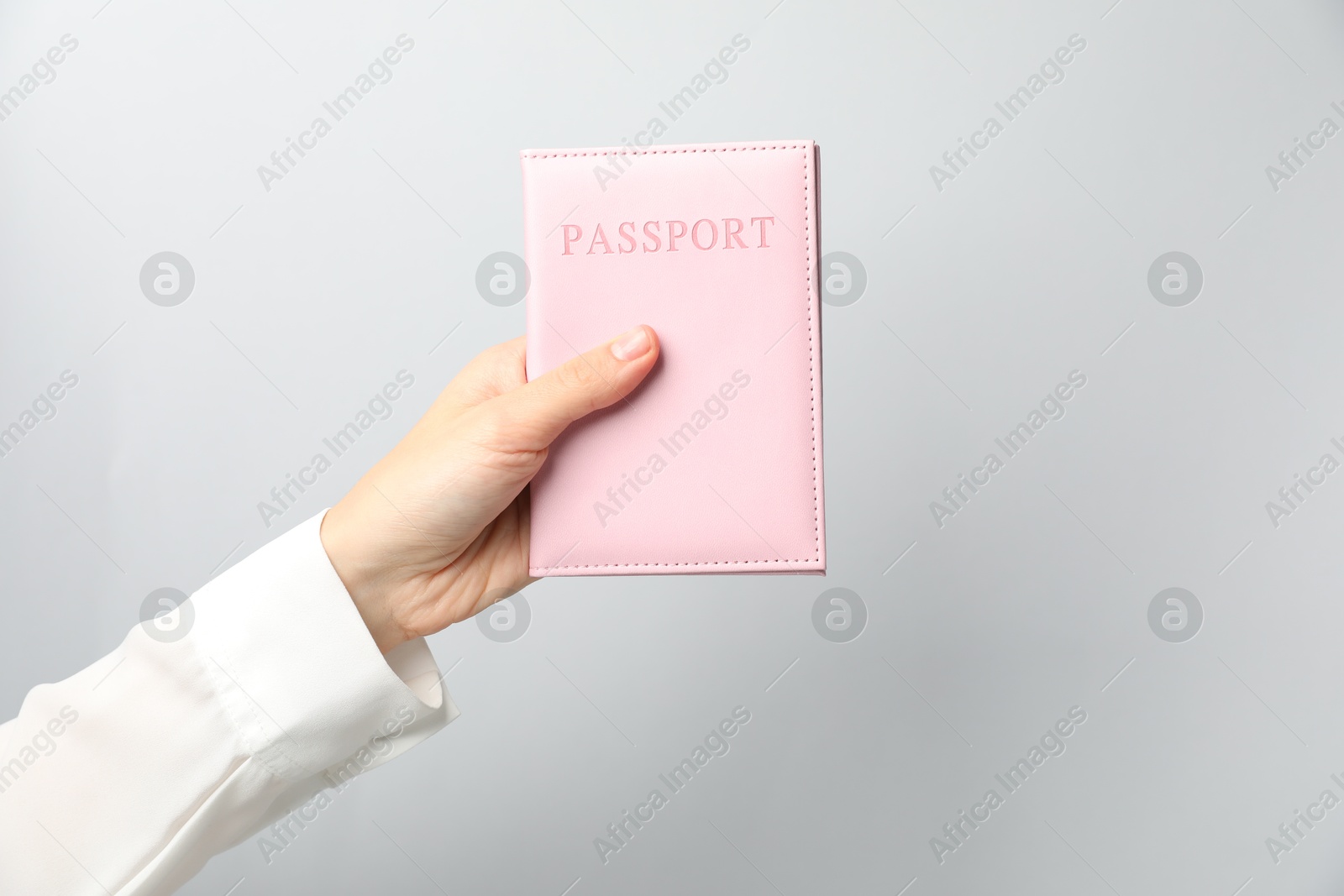 Photo of Woman holding passport in bright cover on grey background, closeup