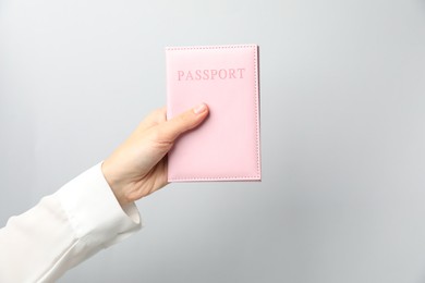 Photo of Woman holding passport in bright cover on grey background, closeup