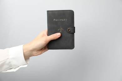 Photo of Woman holding passport in bright cover on grey background, closeup