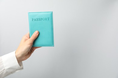 Photo of Woman holding passport in bright cover on grey background, closeup. Space for text