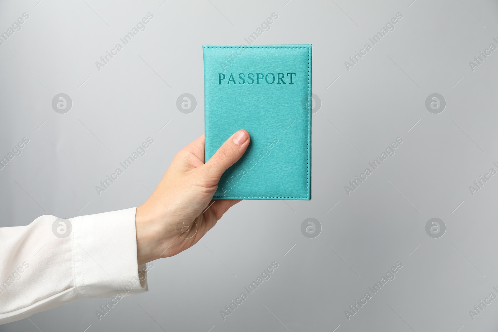 Photo of Woman holding passport in bright cover on grey background, closeup