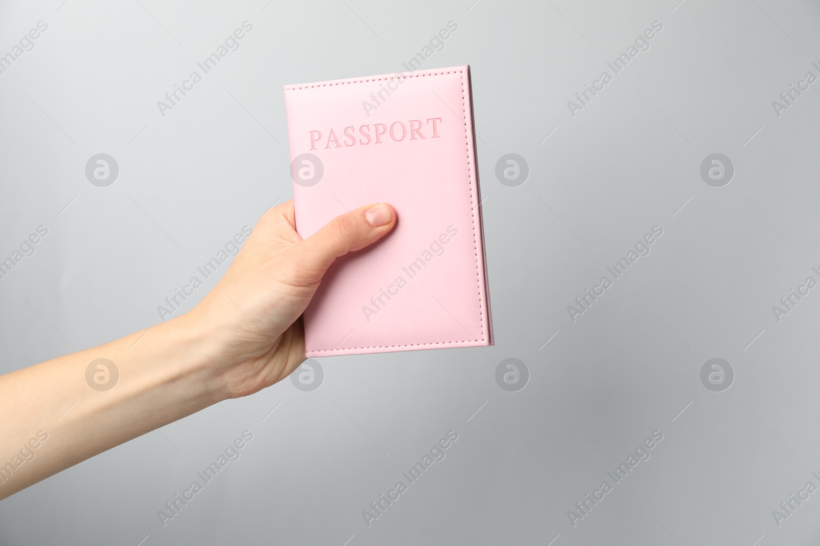 Photo of Woman holding passport in bright cover on grey background, closeup