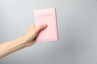 Photo of Woman holding passport in bright cover on grey background, closeup