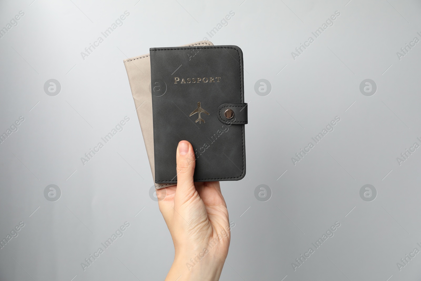 Photo of Woman holding passports in bright covers on grey background, closeup