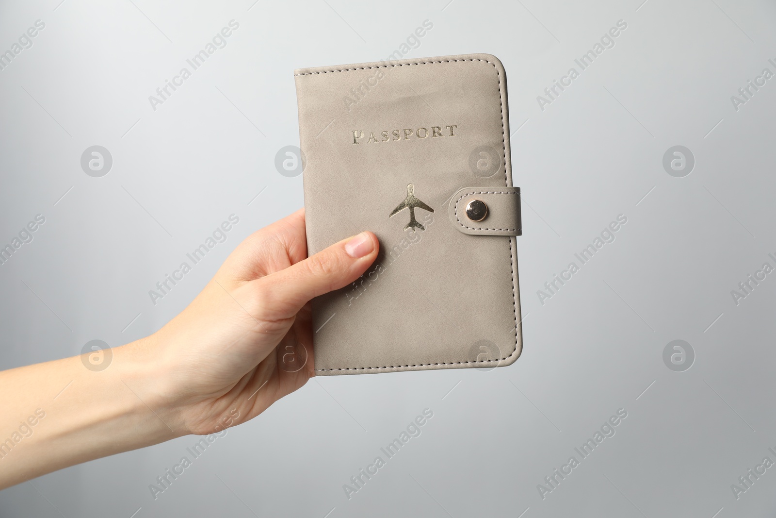 Photo of Woman holding passport in bright cover on grey background, closeup