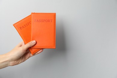 Photo of Woman holding passports in bright covers on grey background, closeup. Space for text